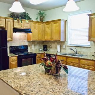 A modern kitchen with granite countertops and wooden cabinets, featuring a central island decorated with plants.