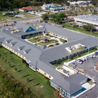Aerial view of a large building with a central courtyard and surrounding parking area.