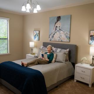 A cozy bedroom with a person reading on the bed, surrounded by elegant decor and artwork.