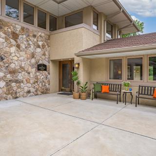 A modern home entrance with stone wall accents, benches, and potted plants.