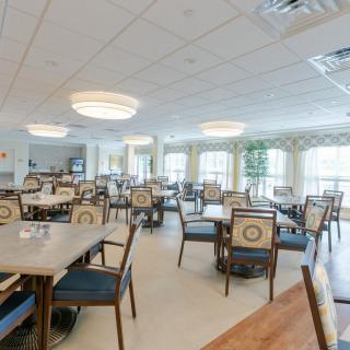 A spacious dining area with multiple tables and chairs, well-lit by large windows and modern light fixtures.
