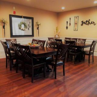 A cozy dining room with wooden tables and chairs, decorated with wall art and soft lighting.