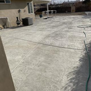 A spacious concrete patio in a residential backyard, showing a clean and open outdoor area.