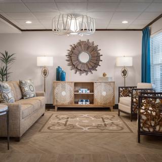 A modern living room with stylish furniture and decor, featuring a large mirror and ambient lighting.