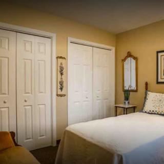 A cozy bedroom with a neatly made bed, double closets, and simple decor.