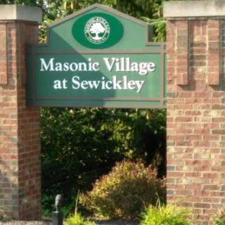 Entrance sign for Masonic Village at Sewickley surrounded by brick pillars and greenery.