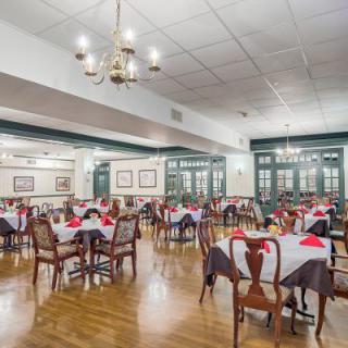 An elegant dining room with neatly arranged tables and chairs, adorned with a chandelier.