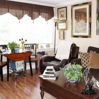 A cozy living room with stylish decor, featuring a table and chairs, leather seating, and artwork on the walls.