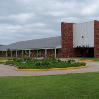 A brick school building with a landscaped entrance under a cloudy sky.
