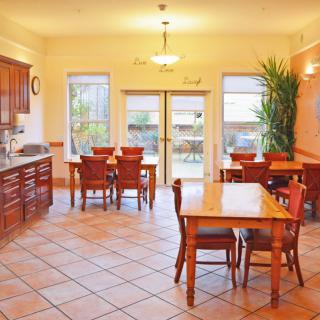 A cozy dining area with wooden furniture and a functional kitchen setup.