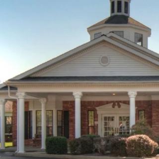 A traditional brick building with a columned entrance and cupola.