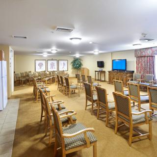 A well-lit conference room with multiple chairs and a television at the front.