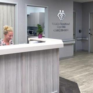 A modern reception area with a white desk and a staff member working.
