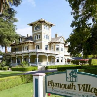 Historic Victorian-style building with lush gardens and a sign reading 'Plymouth Villa'.