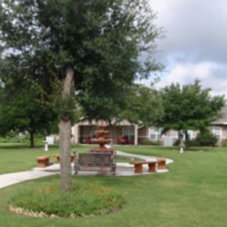 A landscaped garden area featuring a central fountain, surrounded by benches and trees.