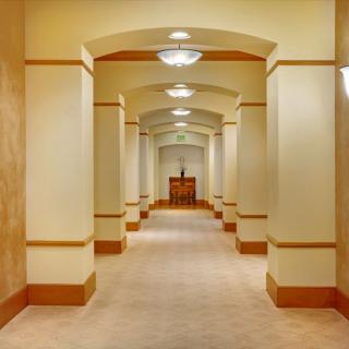 A well-lit hallway with arches and warm-toned walls.