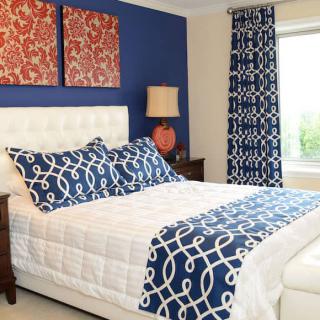 A modern bedroom with blue and white patterned decor and vibrant wall art.