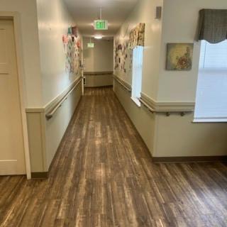 A brightly lit hallway with wooden flooring and handrails along the walls.