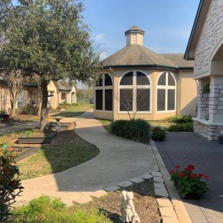 A scenic view of a courtyard with a curved pathway, surrounded by trees and well-maintained landscaping.