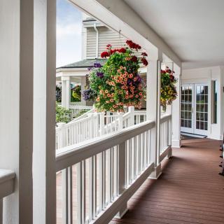 A charming porch with hanging flower baskets, featuring a well-maintained wooden deck and white railing.