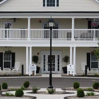 A two-story house with a porch, balcony, and decorative landscaping.