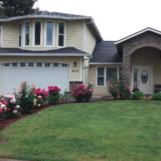 A two-story suburban house with a well-maintained front yard and colorful flowers.