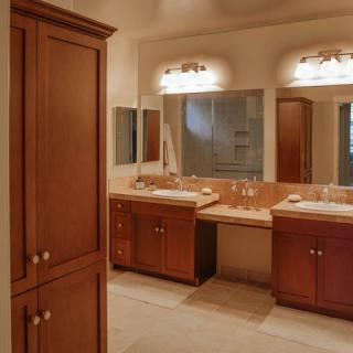 A spacious bathroom with double sinks, wooden cabinets, and large mirrors.