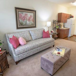 A cozy living room with a patterned sofa and colorful pillows, complemented by a painting and soft lighting.
