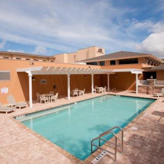 An inviting outdoor swimming pool area with chairs and a patio, perfect for relaxation on a sunny day.
