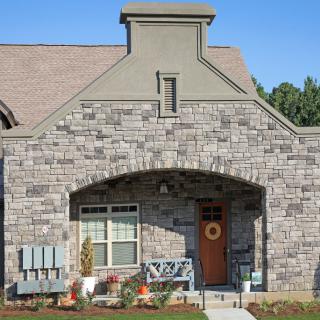 A charming stone-faced house with a welcoming front porch and decorative wreath on the door.