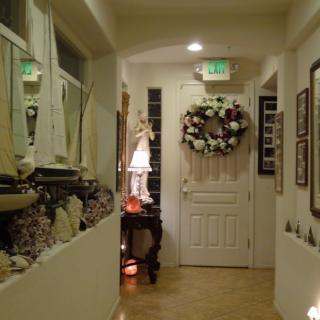 A cozy hallway with nautical decorations, featuring a large wreath on the door and a lamp on a side table.