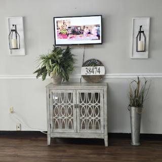 A stylish living room setup featuring a TV, decorative cabinet, and artwork on the walls.