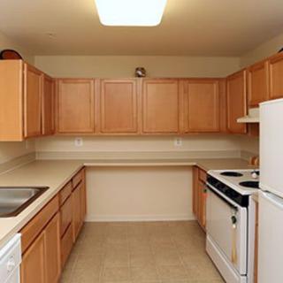 A compact kitchen with wooden cabinets and basic appliances.
