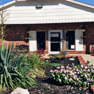 A brick house with a well-maintained garden featuring various flowers and plants.