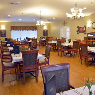 A spacious dining area with neatly arranged tables and chairs, illuminated by chandeliers.