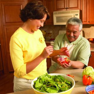 A couple preparing a fresh salad together in the kitchen.