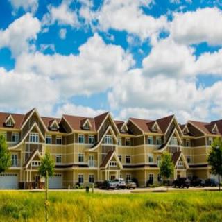 A row of suburban townhouses under a partly cloudy sky.