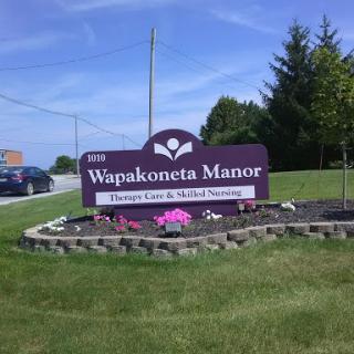 Sign for Wapakoneta Manor, indicating a care facility in a peaceful outdoor setting.