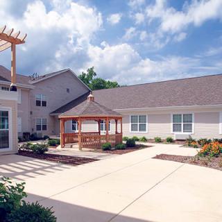 A serene courtyard with a gazebo and well-maintained landscaping in front of a residential building.