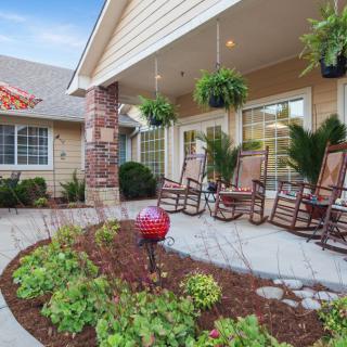 A cozy porch with rocking chairs and lush greenery, inviting relaxation.