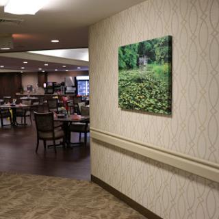 A tranquil wall art depicting a lush green landscape, enhancing the inviting atmosphere of the dining area.
