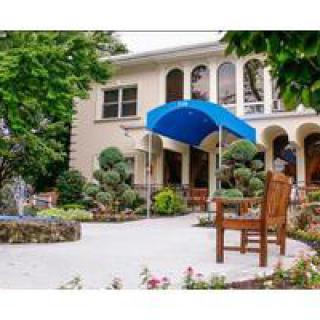 A building with a blue awning, surrounded by a landscaped garden and benches.
