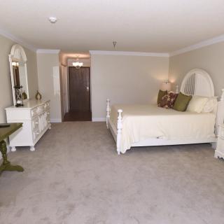 A spacious bedroom with elegant white furniture and neutral decor.