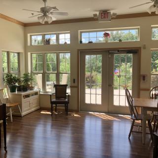 A bright and cozy sunroom with large windows, wooden floors, and a variety of plants.