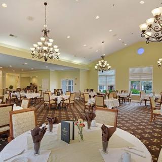 An elegant dining room with chandeliers, well-set tables, and comfortable seating.