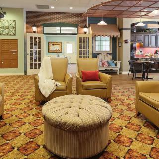 A cozy living room featuring a seating area with several armchairs, an ottoman, and warm decorative elements.