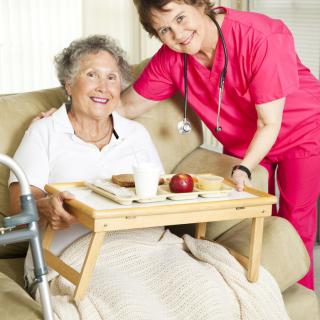 A caregiver assists an elderly woman with her meal at home.