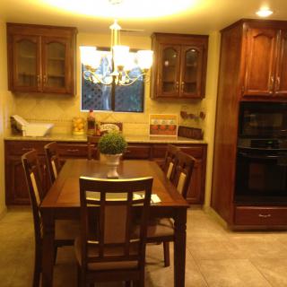 A cozy kitchen and dining area with wooden furniture, featuring a chandelier and built-in cabinets.