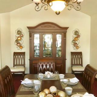 A cozy dining room with a wooden table set, china cabinet, and elegant chandelier.