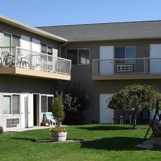 Exterior view of a residential apartment building with balconies and a well-maintained lawn.